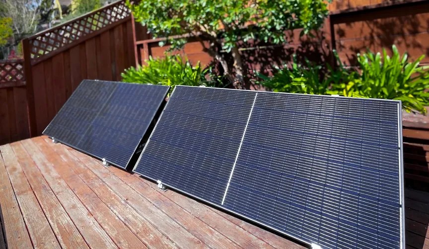 A solar panel on a deck, propped next to an elevated garden bed.