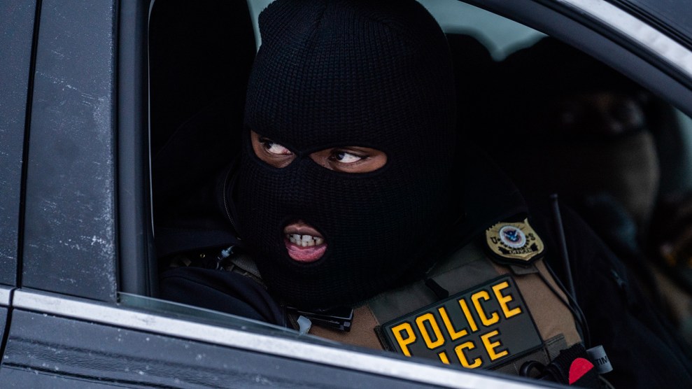 Close up of an ICE agent wearing a ski mask, sitting in an SUV.