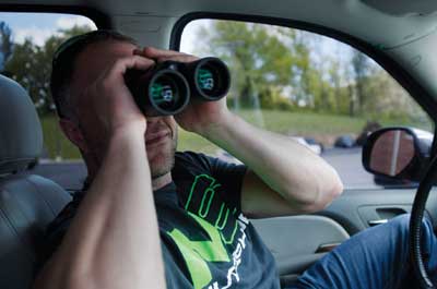 A guy in a car with binoculars