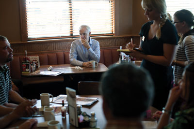 Bob Kerrey sits in a Scottsbluff diner, waiting to meet with ranchers and farmers.